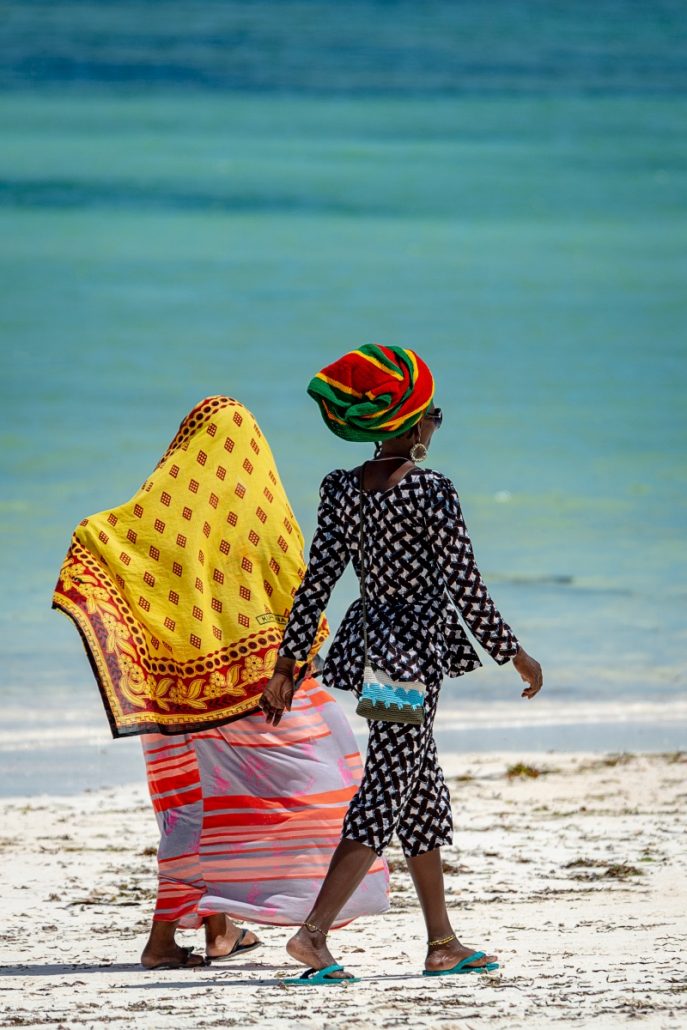 Portrait of two colourful and fashionably dressed women on the beach of Zanzibar.