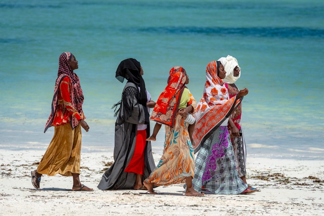 Portrait of five colourful and fashionably dressed women on the beach of Zanzibar.