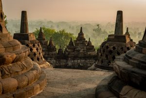 Landscape shot of stupas in the morning light in front of a forest.