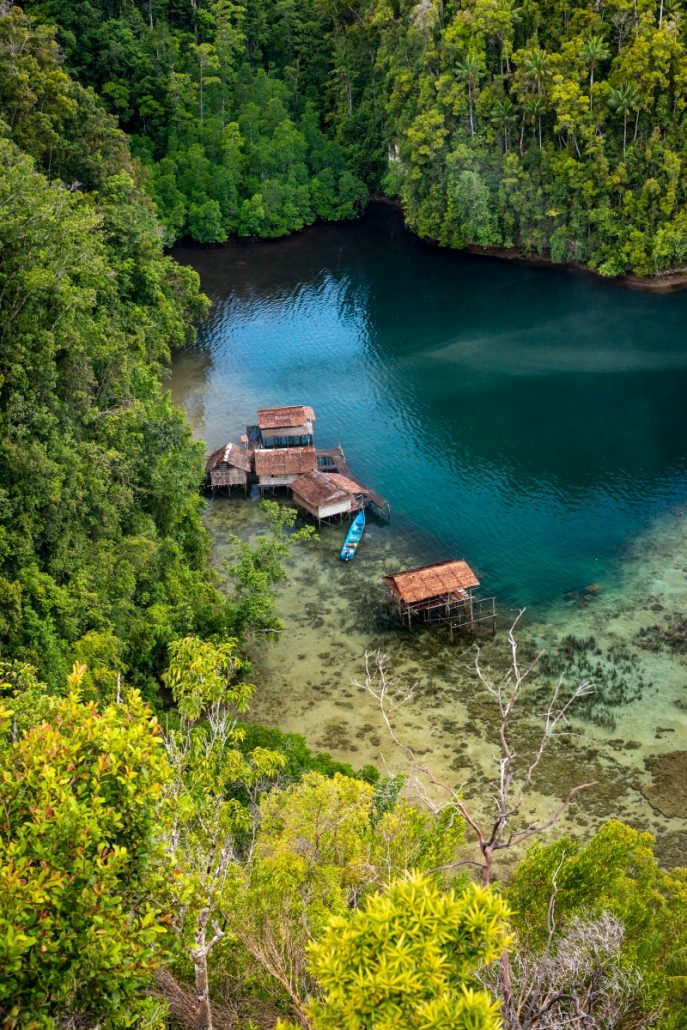Landscape photograph of fishermen's huts in a tropical bay surrounded by jungle.