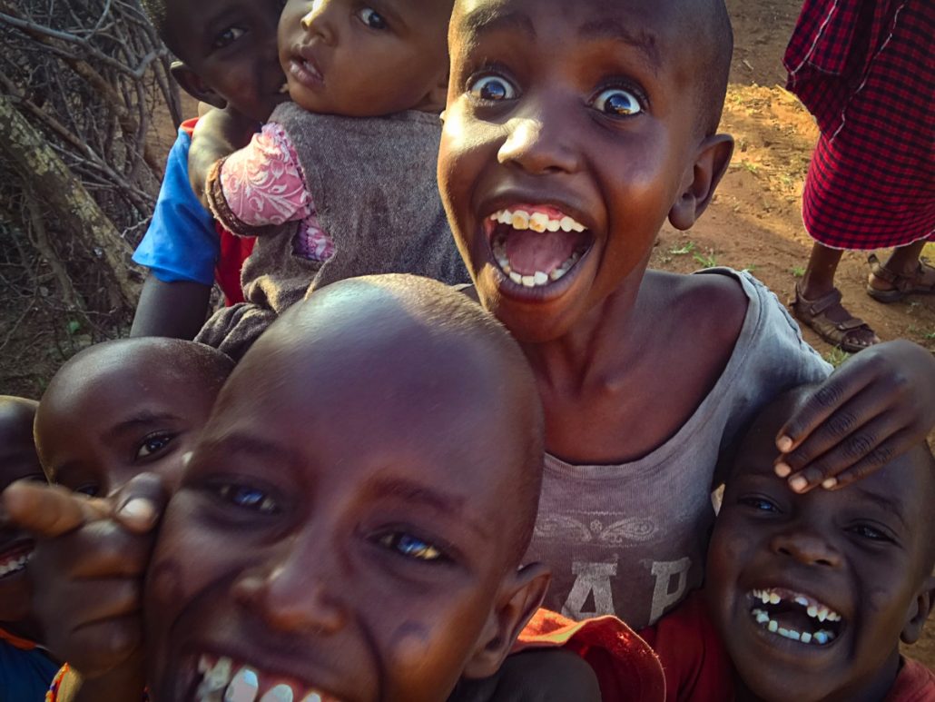 Group photo of seven laughing Massai children.