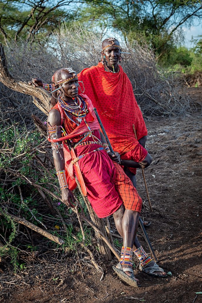 Portrait of two traditionally dressed Masai warriors with cane in a village near the Masai Mara.