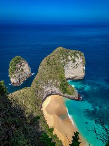 Landscape shot of a bay with a single rock in the sea.
