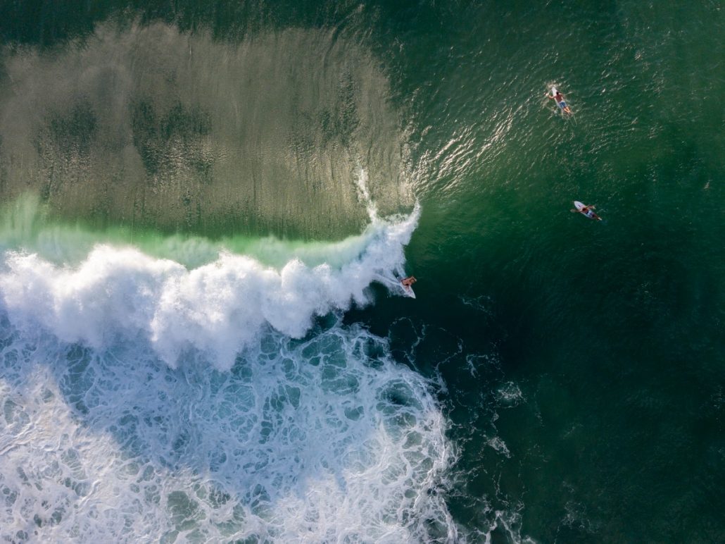 Aerial view of a green wave with surfers.