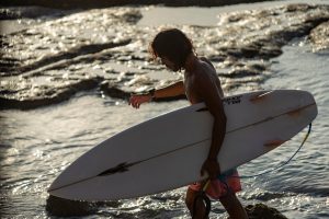 Portrait of a surfer with a surfboard under his arm.