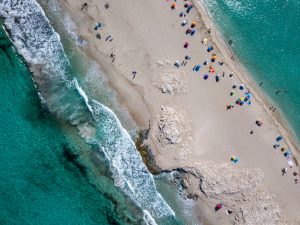 Aerial shot of a narrow beach with sunshades.