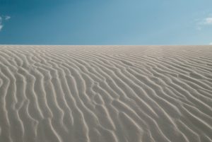 Landscape photograph of the waves on the surface of a white sand dune.
