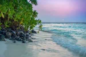 Landscape shot of small waves on a beach at sunset.
