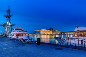 Night photography of the illuminated building between two boats.