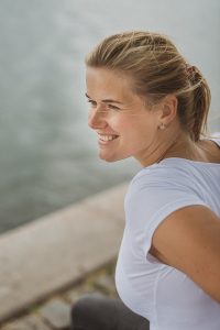 Portrait photograph of a smiling woman with white top.