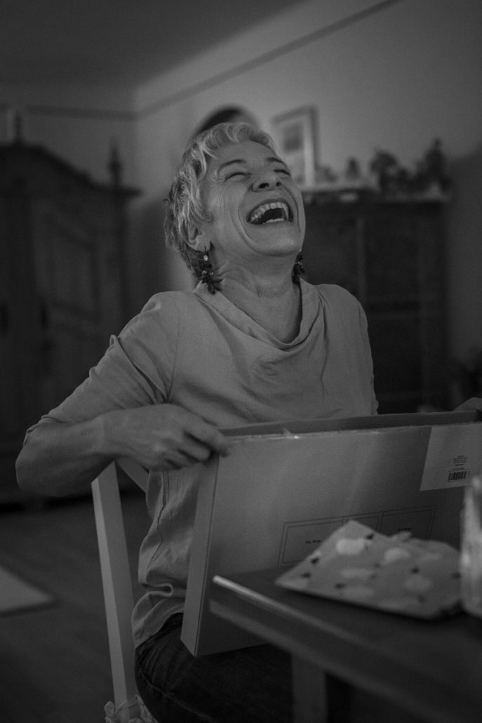 Black and white portrait of a laughing woman unwrapping a gift.