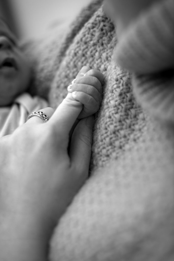Black and white portrait of a baby hand clasping the mother's finger.