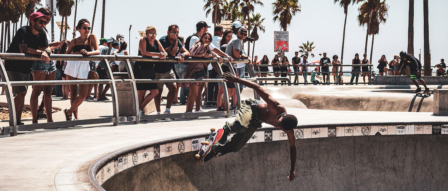 Portrait of a skater in a skate park in Venice Beach in front of palm trees and the audience.