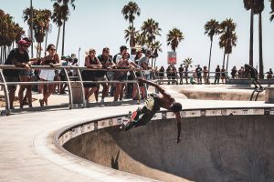 Portrait of a skater in a skate park in Venice Beach in front of palm trees and the audience.