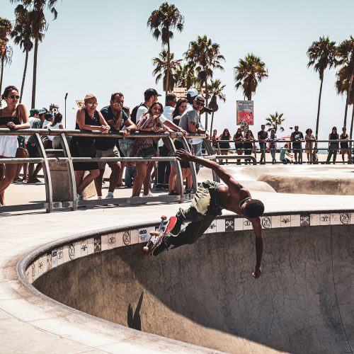 Portrait of a skater in a skate park in Venice Beach in front of palm trees and the audience.