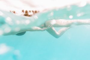 Underwater split photo of a woman snorkeling in front of palm trees.