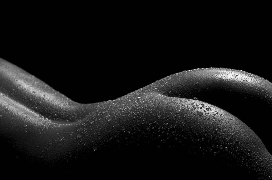 Black and white close-up and lowkey of a female bottom sprinkled with water drops.