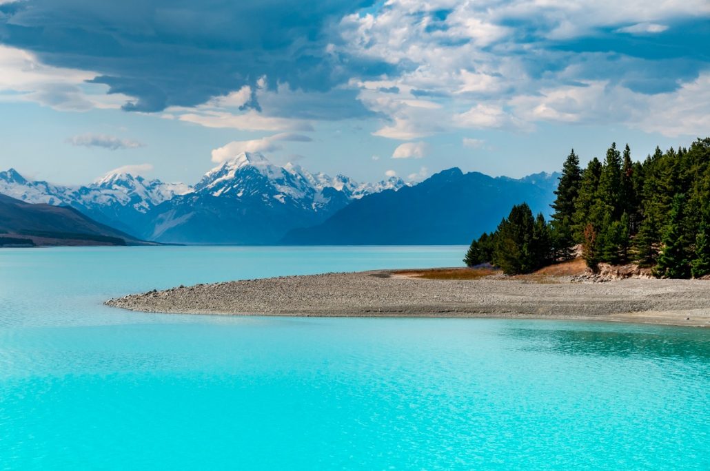 Landscape shot of a turquoise lake in front of snow-covered mountains.