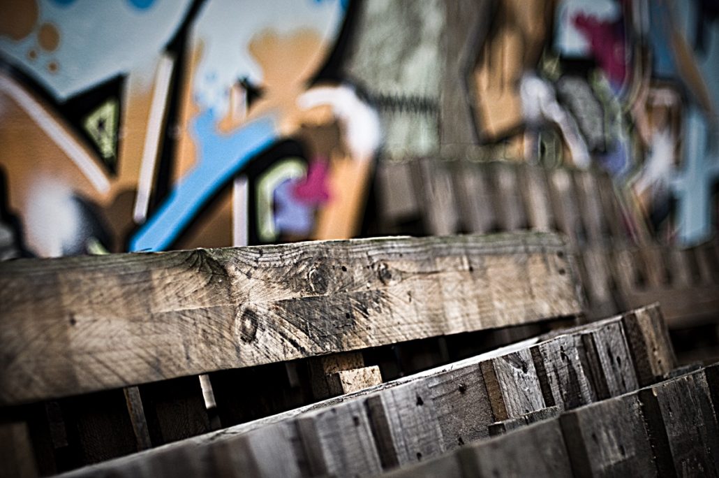 Urban photograph of wooden pallets in front of a sprayed wall.