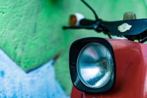 Urban close-up of a red scooter from a green wall.