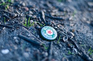 Urban photograph of a crown cork on earth.