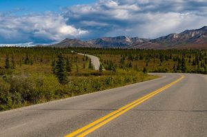 Landscape shot of a road winding through a wooded landscape.