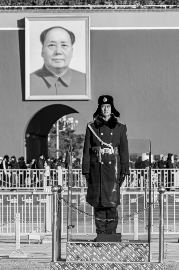 Portrait Picture of a guard in front of a portrait of Mao.
