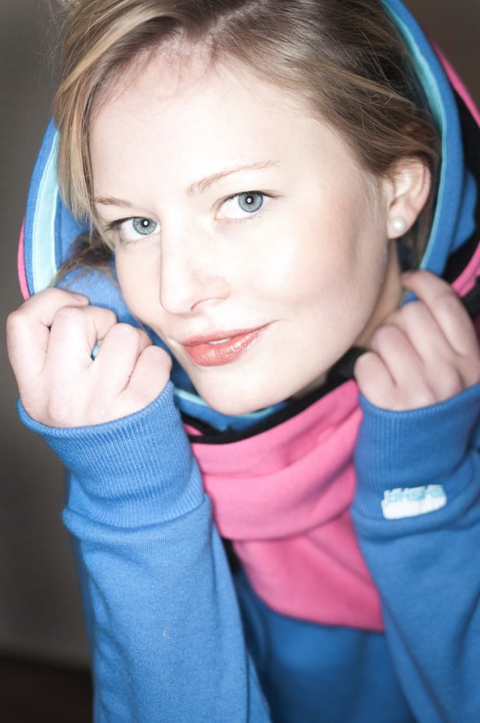 Portrait photo of a strong, young woman with blue hoodie.