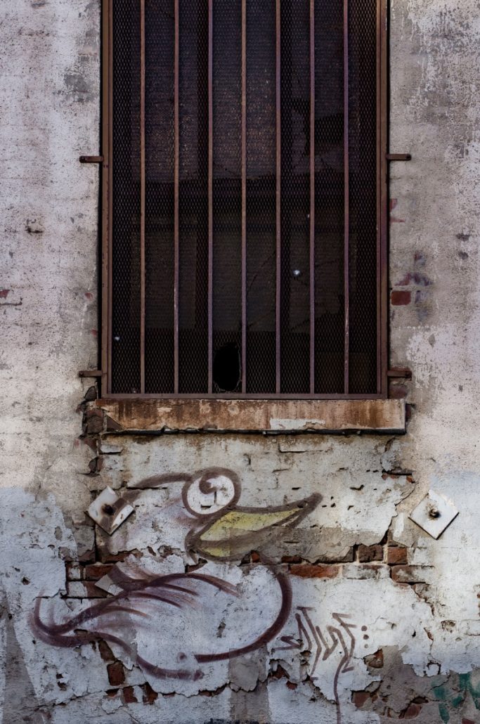 Urban shot of wall art under a barred window.