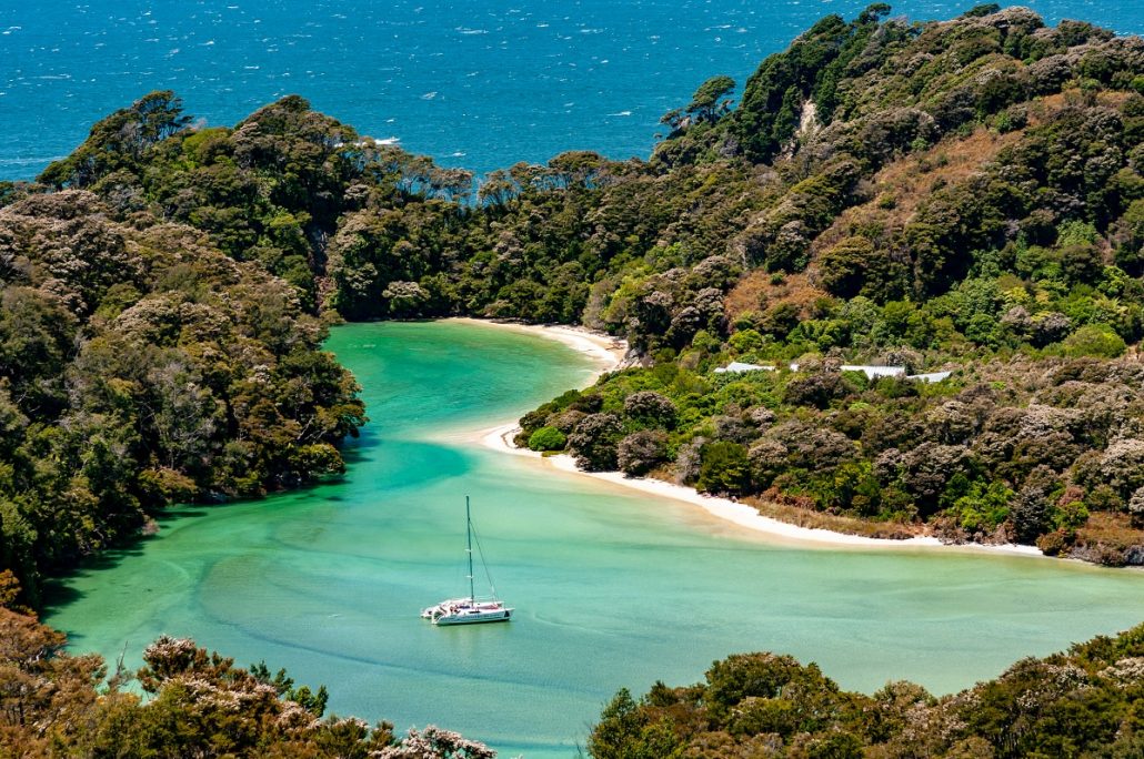 Landscape shot of a bay with beach surrounded by lush green vegetation.