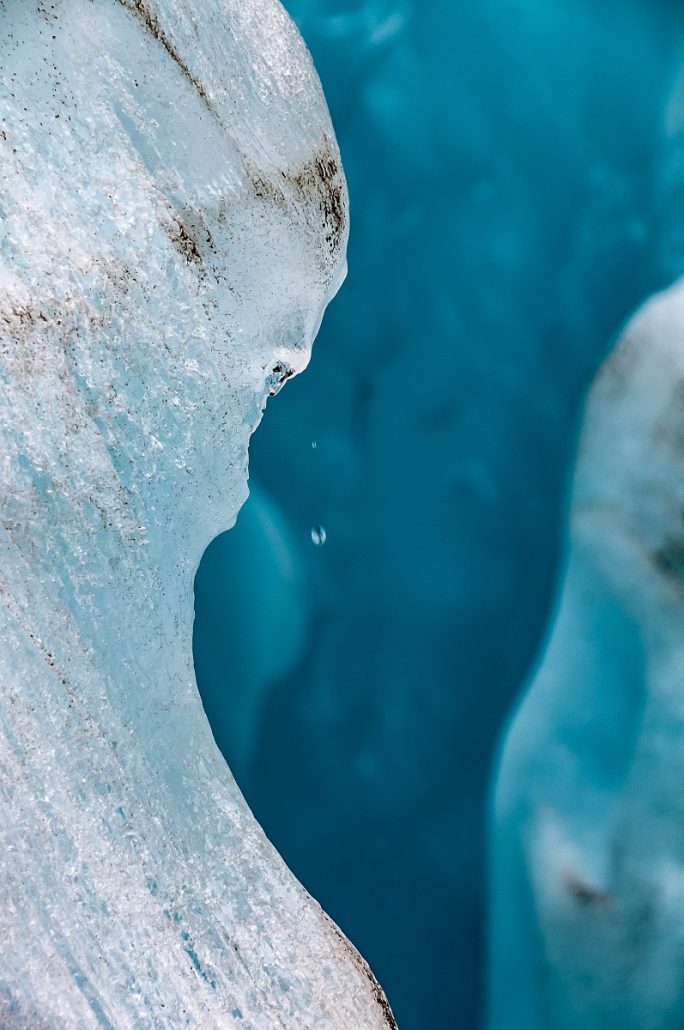 Close-up of a drop of water falling from a melting part of a glacier.